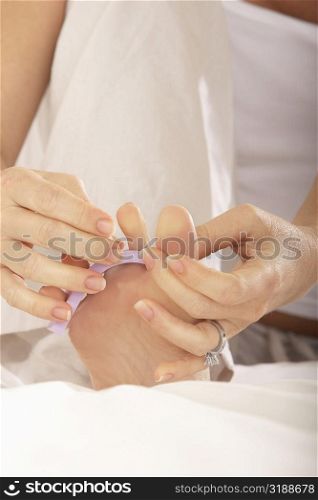 Low section view of a mid adult woman adjusting her toenail divider