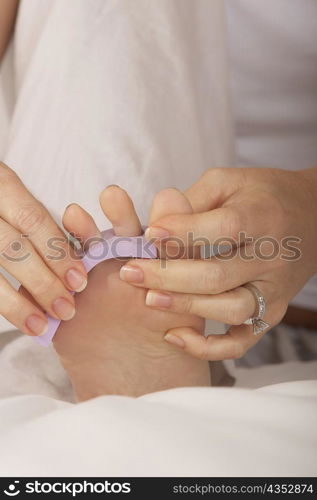 Low section view of a mid adult woman adjusting her toenail divider