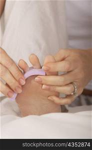 Low section view of a mid adult woman adjusting her toenail divider