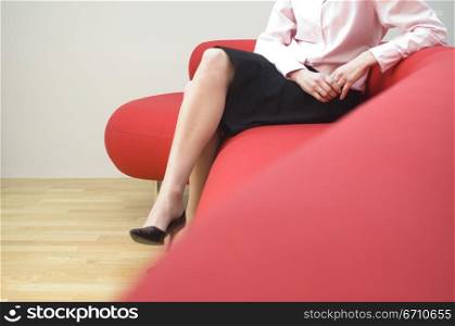 Low section view of a mid adult woman sitting on a couch
