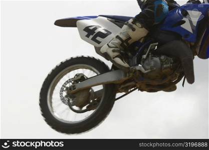 Low section view of a motocross rider performing jump on a motorcycle