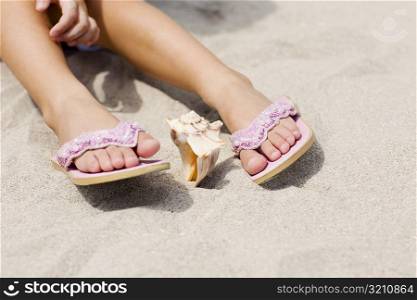 Low section view of a person&acute;s feet near a conch shell