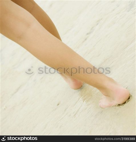 Low section view of a person walking on sand