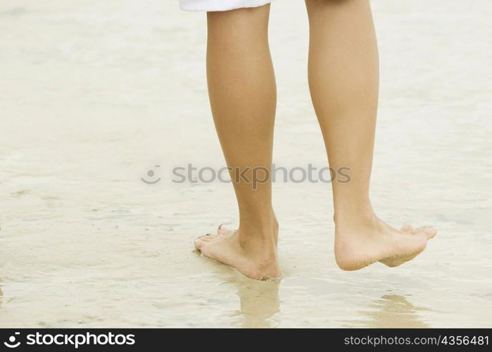 Low section view of a person walking on sand