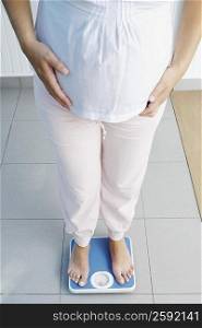 Low section view of a pregnant woman standing on a weighing scale