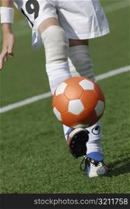 Low section view of a soccer player balancing a soccer ball