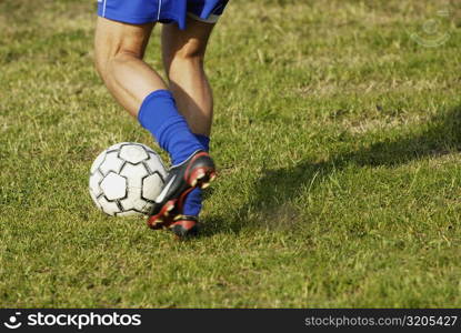 Low section view of a soccer player dodging a soccer ball