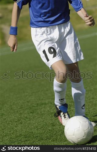 Low section view of a soccer player running with a soccer ball