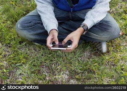 Low section view of a teenage boy using a mobile phone