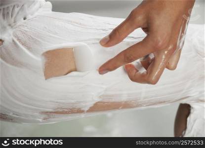 Low section view of a woman applying shaving cream on her leg