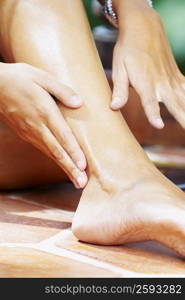 Low section view of a woman applying suntan lotion on her leg