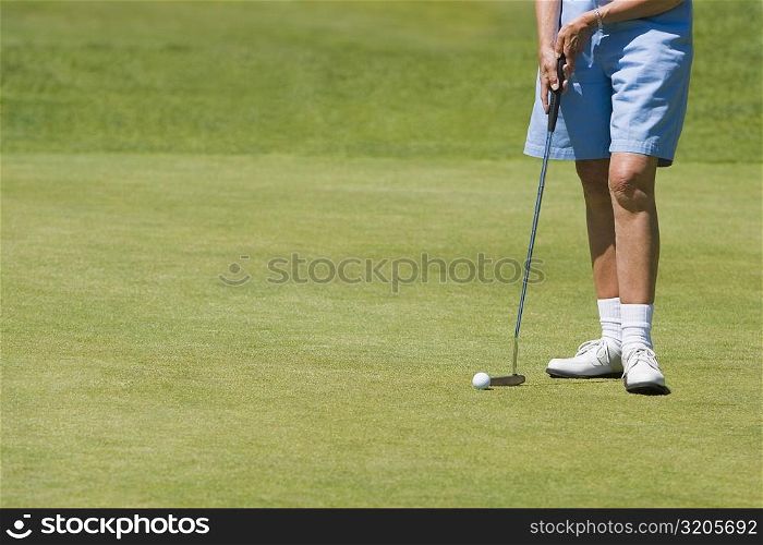 Low section view of a woman holding a golf club on a golf course