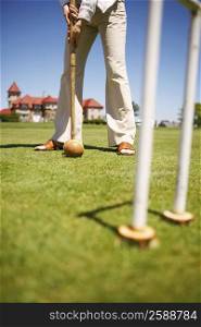 Low section view of a woman playing croquet in a field