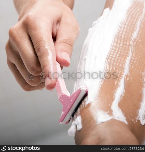 Low section view of a woman shaving her leg with a razor