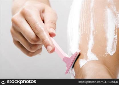 Low section view of a woman shaving her leg with a razor