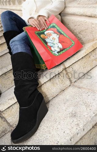 Low section view of a woman sitting on steps with shopping bags