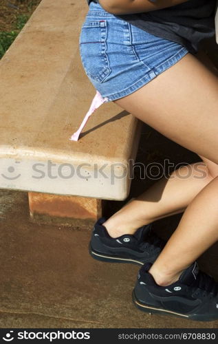 Low section view of a woman standing up from a bench with sticking bubble gum on her buttocks