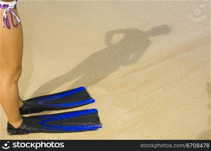 Low section view of a woman wearing flippers standing on the beach