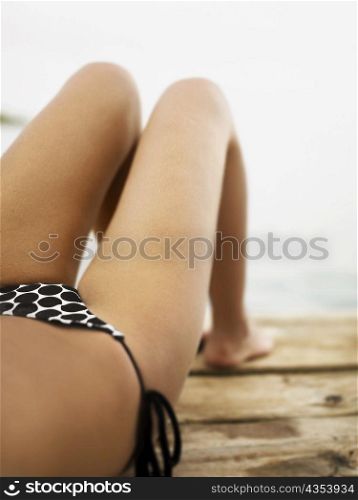 Low section view of a young woman lying on a wooden surface