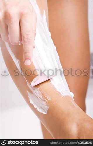 Low section view of a young woman shaving her legs