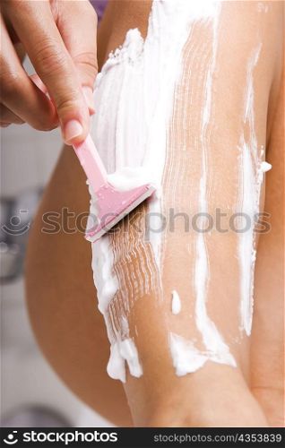Low section view of a young woman shaving her legs
