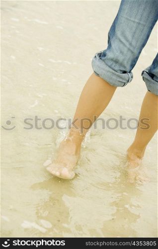 Low section view of a young woman standing on the beach