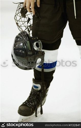 Low section view of an ice hockey player holding a helmet