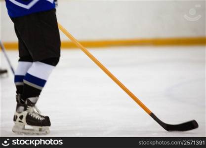 Low section view of an ice hockey player holding an ice hockey stick