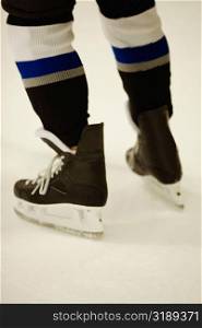 Low section view of an ice hockey player wearing ice skates