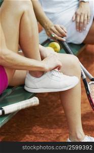 Low section view of female tennis player tying her shoelaces