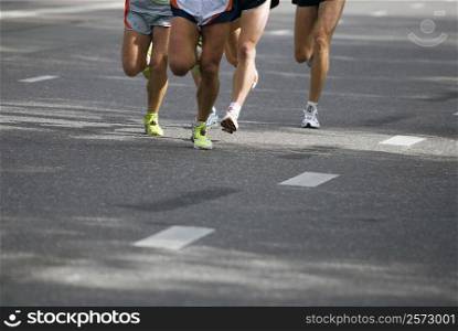 Low section view of male athletes running on a road