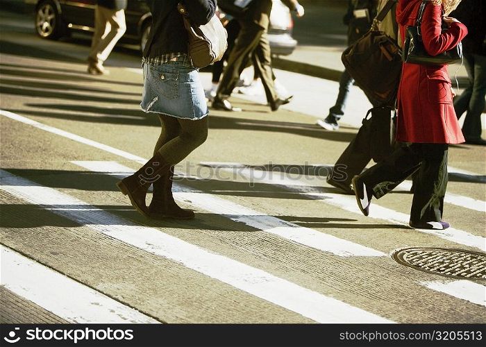 Low section view of men and women walking on the road