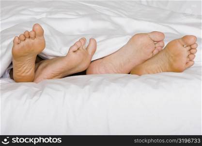 Low section view of the feet of two people on a bed