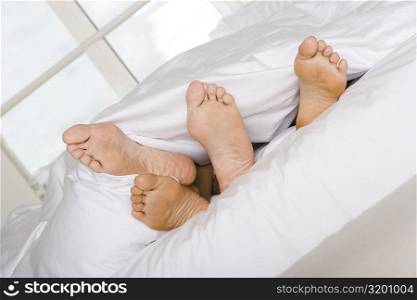 Low section view of the feet of two people on a bed