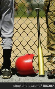 Low section view of two boys standing on either sides of a chain-link fence