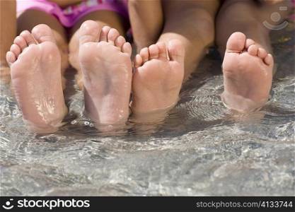 Low section view of two girls sitting in water