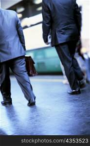 Low section view of two men walking at a railroad station platform, Rome, Italy