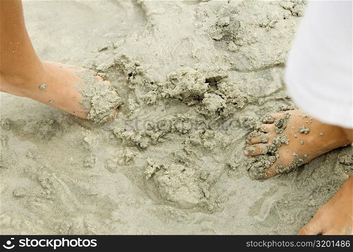 Low section view of two people&acute;s feet in sand