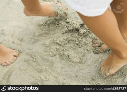 Low section view of two people&acute;s feet in sand