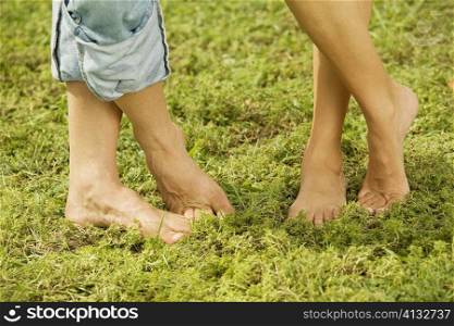 Low section view of two people standing bare feet on the grass