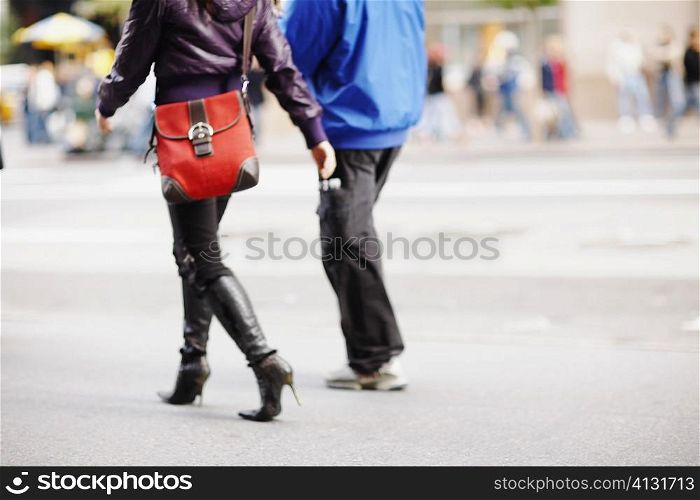 Low section view of two people walking and carrying bags