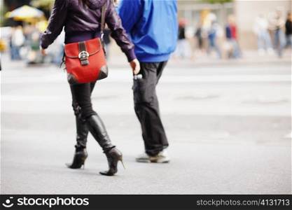 Low section view of two people walking and carrying bags