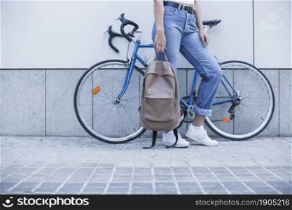 low section young woman standing near bicycle holding backpack. Beautiful photo. low section young woman standing near bicycle holding backpack