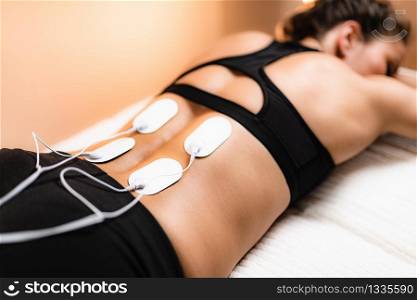 Lower Back Physical Therapy with TENS Electrode Pads, Transcutaneous Electrical Nerve Stimulation. Electrodes onto Patient&rsquo;s Lower Back. Lower Back Physical Therapy with TENS Electrode Pads, Transcutaneous Electrical Nerve Stimulation