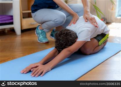 Lower back stretch. Boy exercising with physical therapist.. Lower back stretch with physical therapist.