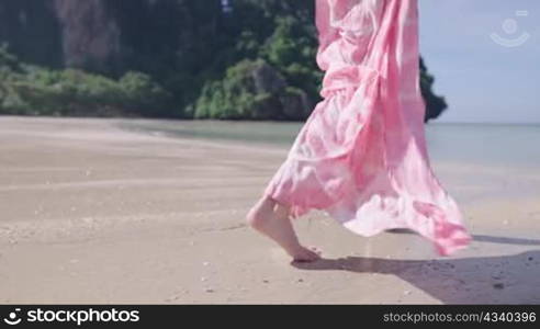 Lower body part females in pink beachwear running into the ocean on the tropical island beach, sea water splashing in slow motion. Summer holiday travel destination paradise on earth fun and joyful