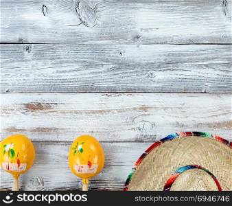 Lower border of traditional maracas and large sombrero for Cinco de Mayo holiday celebration on weathered white wooden boards