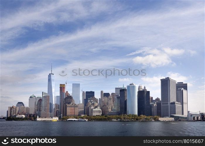 lower manhattan skyline above waterfront with blue sky and clouds seen from the south