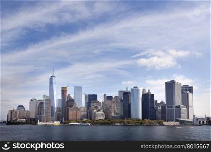 lower manhattan skyline above waterfront with blue sky and clouds seen from the south