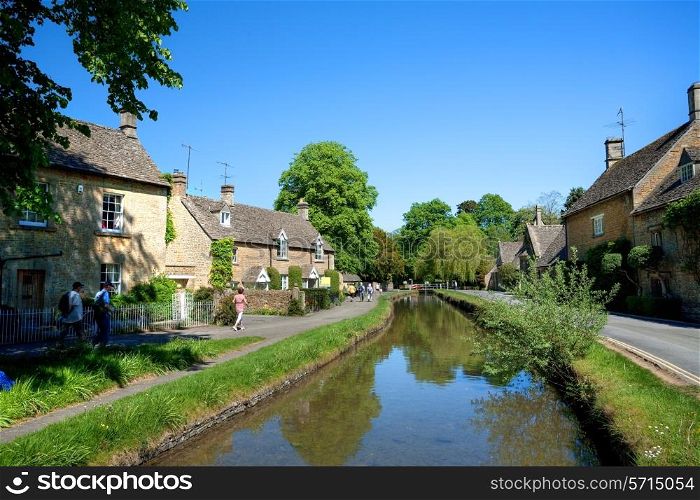 Lower Slaughter, Gloucestershire, UK ? May 23, 2010: Tourists enjoying the sunshine at the pretty Cotswold village of Lower Slaughter near Bourton on the Water.